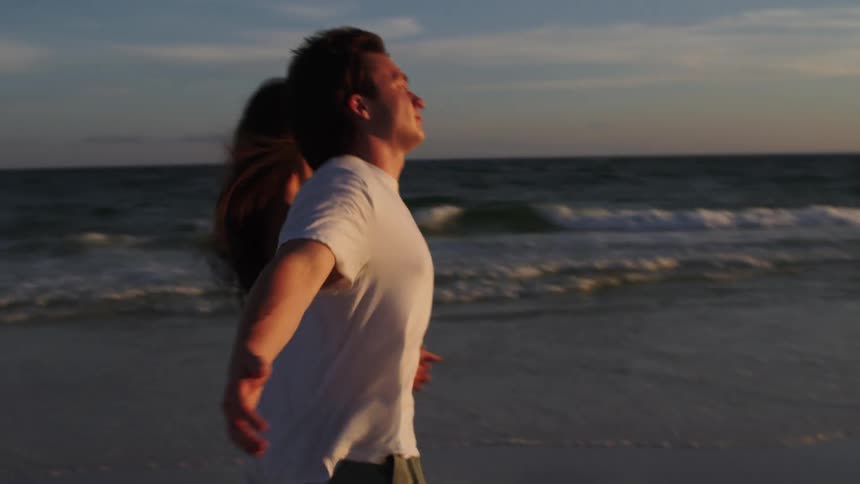 Couple holding hands walking along the beach