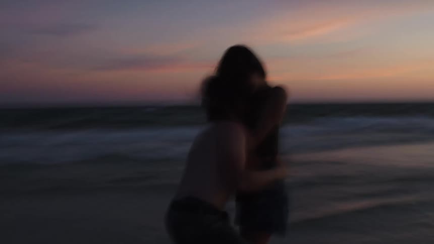 A couple having fun on the beach playing together at sunset