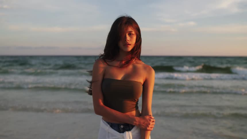 A woman at the beach looks at the camera