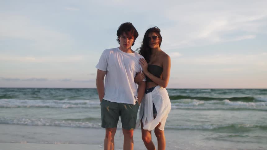 Young couple standing together on the beach as waves roll into shore