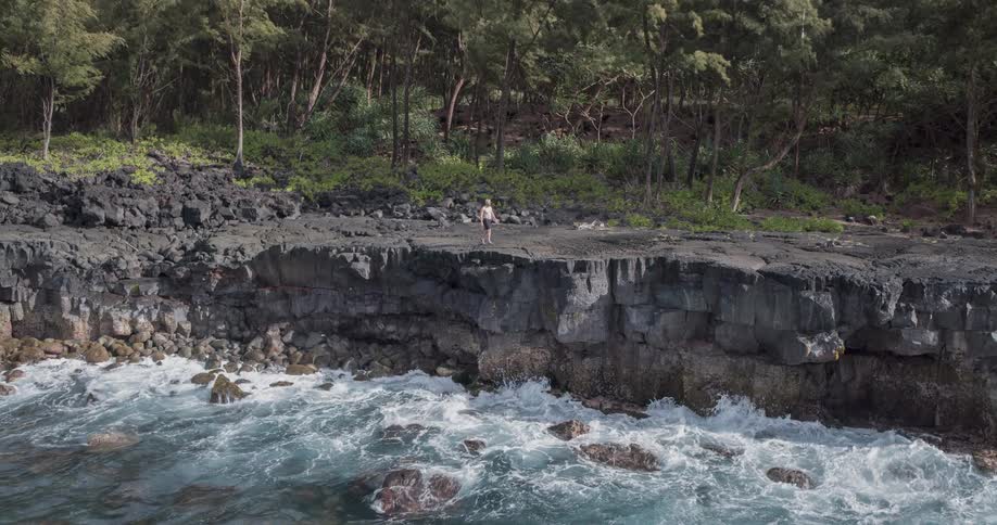 A man is walking along the cliff at the waterfront