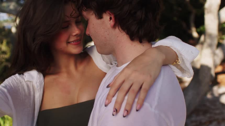 A couple having fun holding and hugging each other in the woods at midday both smiling