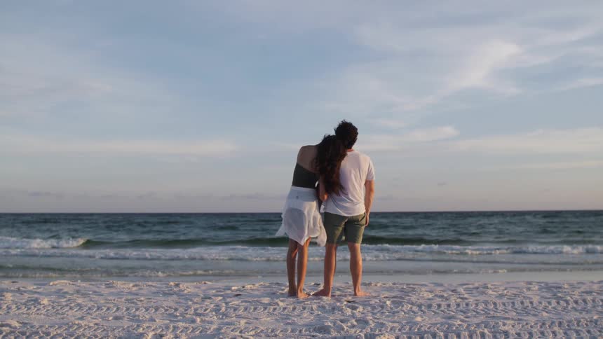 Couple standing on the sand looking at the sea