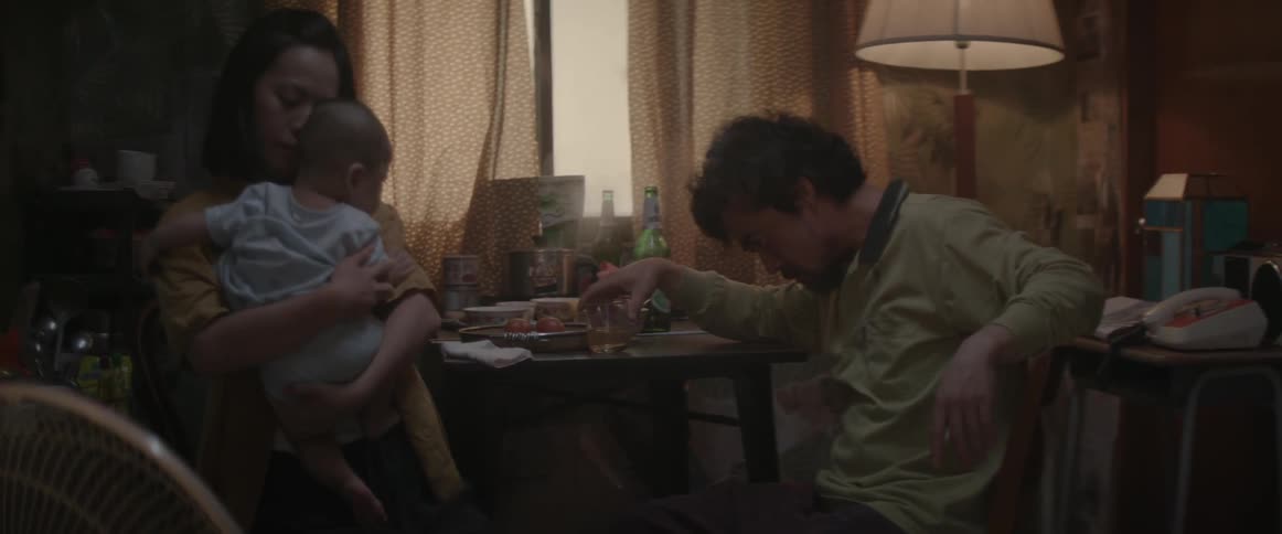 A man is drinking and smoking near  woman and child