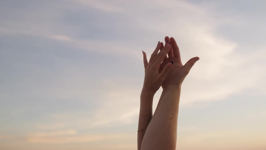 A person clasps their hands in the air