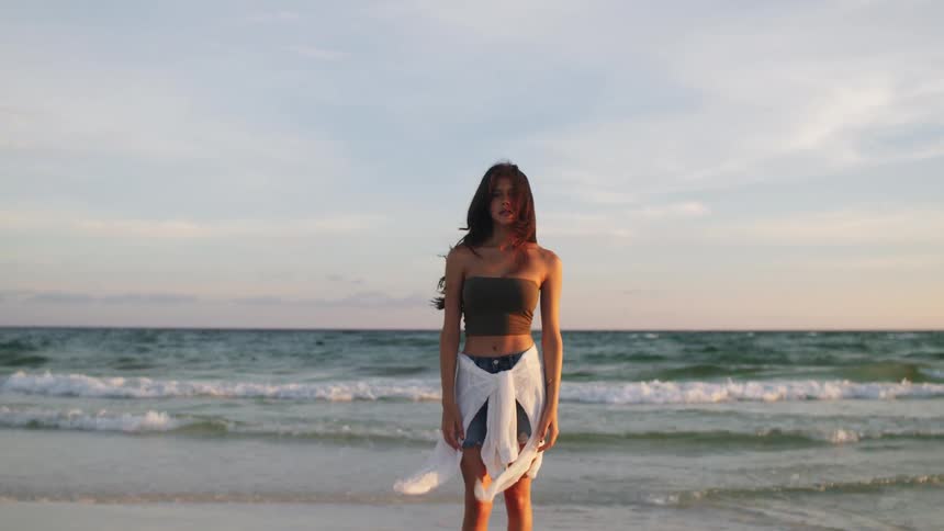 Young woman standing on the beach as waves roll into shore