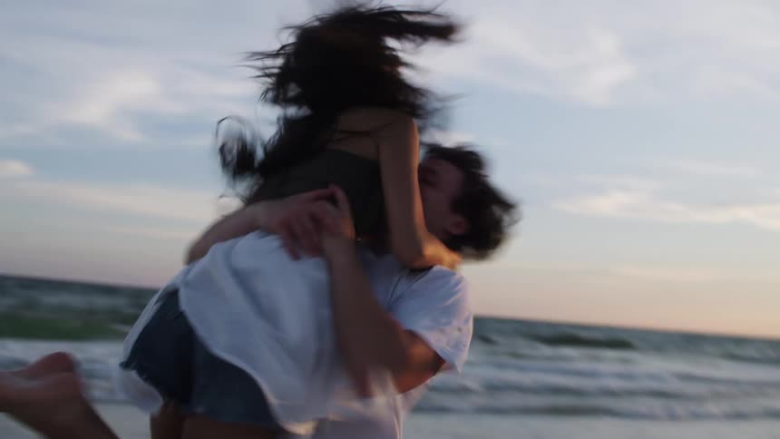 A couple run up and hug each other on the beach
