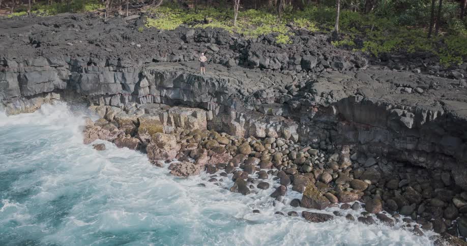 A man stands by the cliff of the ocean