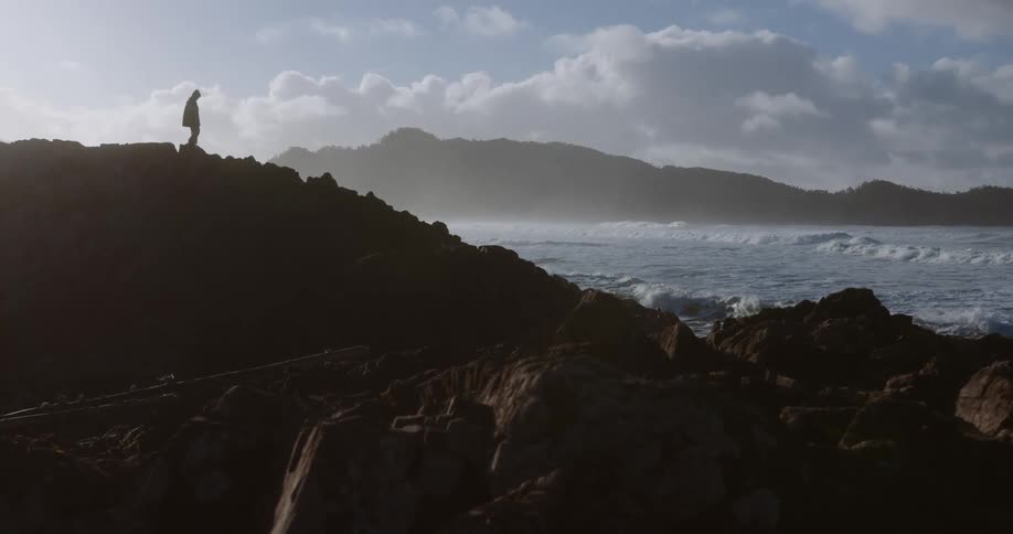 The man walks on the rocks by the water