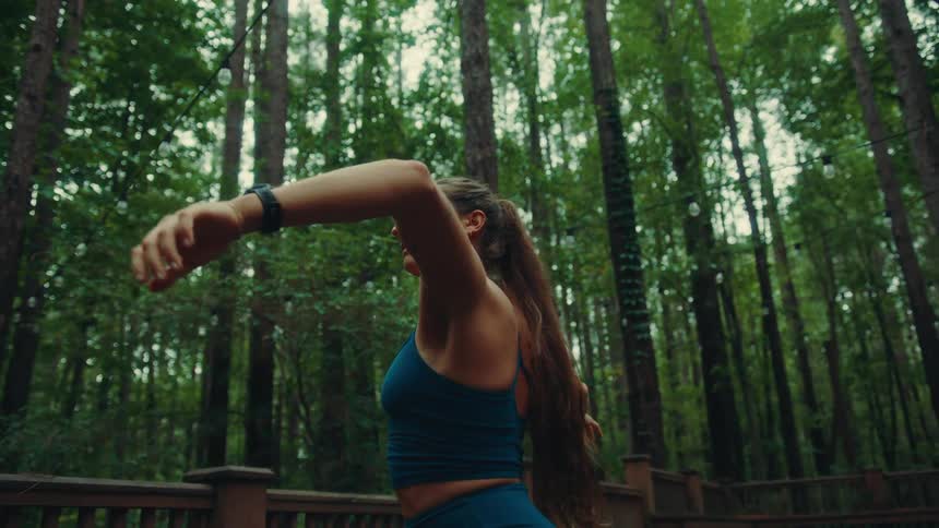 A young woman outdoors in the woods doing yoga at midday