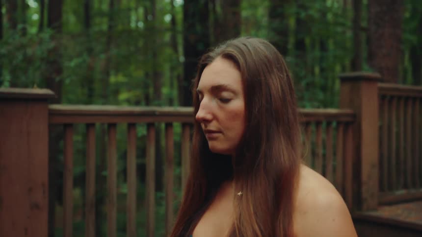 The woman is meditating on the deck