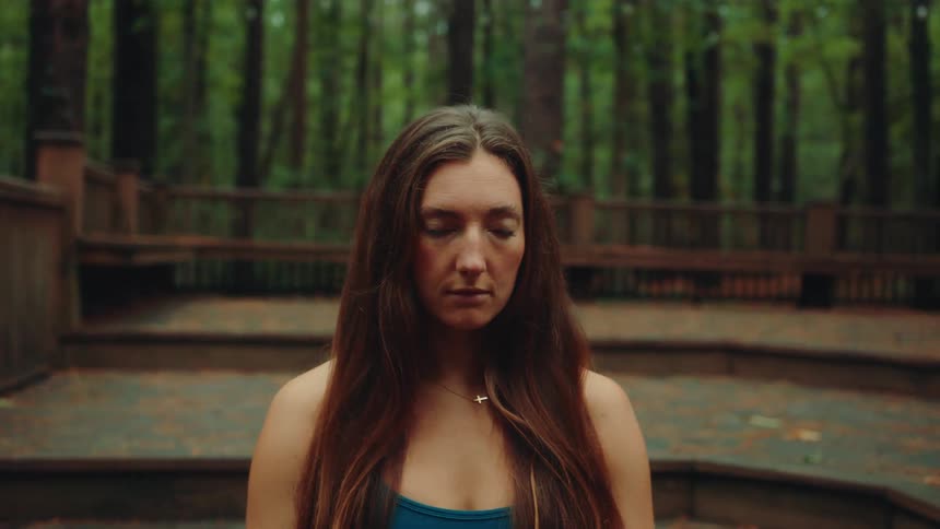 Woman on a wooden deck in a forest setting looking up
