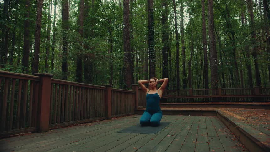 The woman ties her hair back and does yoga