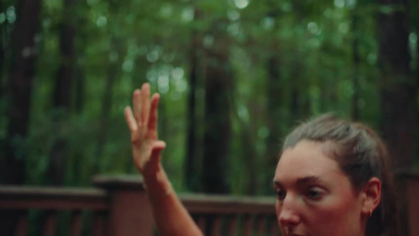 A woman does some stretches while outdoors in the forest