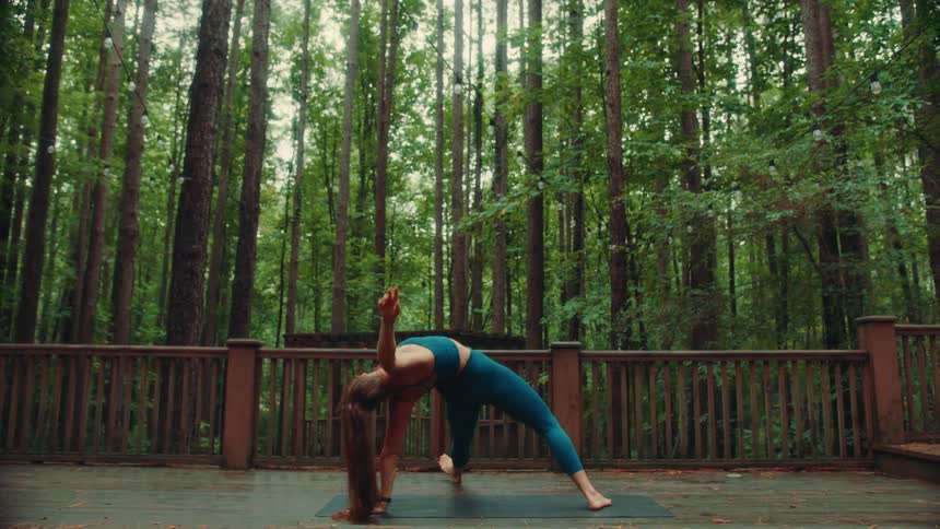 A woman doing yoga stretches on a forest parks walkway
