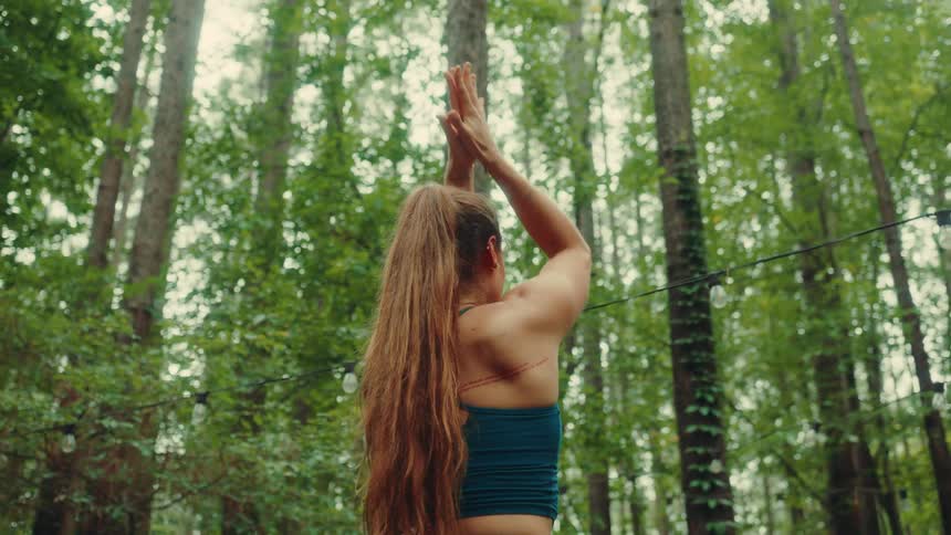 Woman in blue top doing yoga outdoors in the forest