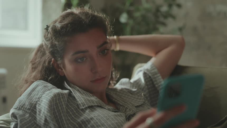 Woman lying on the couch looking at her phone