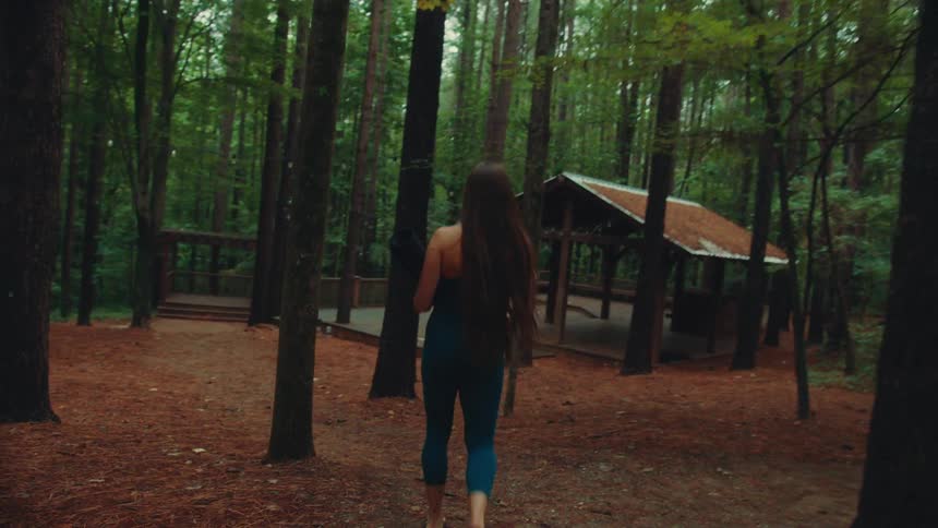 Woman in blue sportswear walking towards a wooden deck in the forest