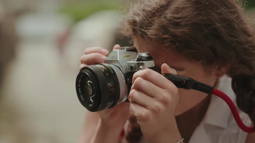 A woman focuses her vintage 35mm film camera