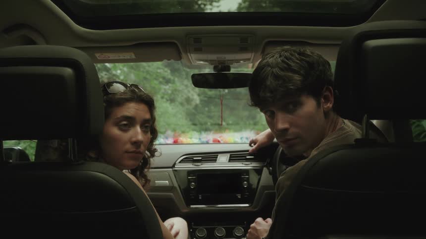 Couple sitting in the front seats of a car looking back