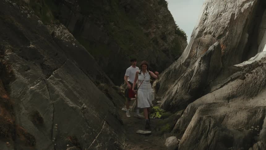Woman and man walking along a trail between large rock formations
