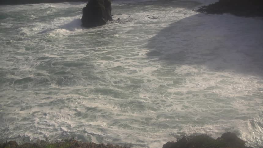 View from atop a hill of foamy white ocean waters