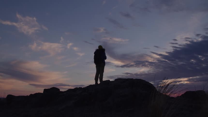 Person standing on rocks watching the sunset