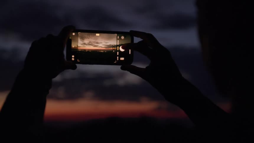 Person photographing the sunset with a cellphone