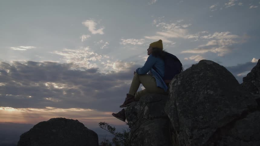 A woman sits atop some rocks