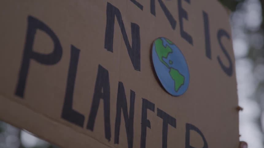 Hands holding up a cardboard sign saying there is no planet b