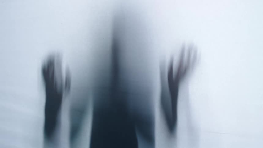 Ghostly shadow figure of person behind white surface