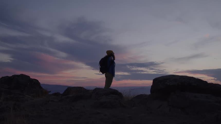Hiker wearing a backpack stands in the mountains