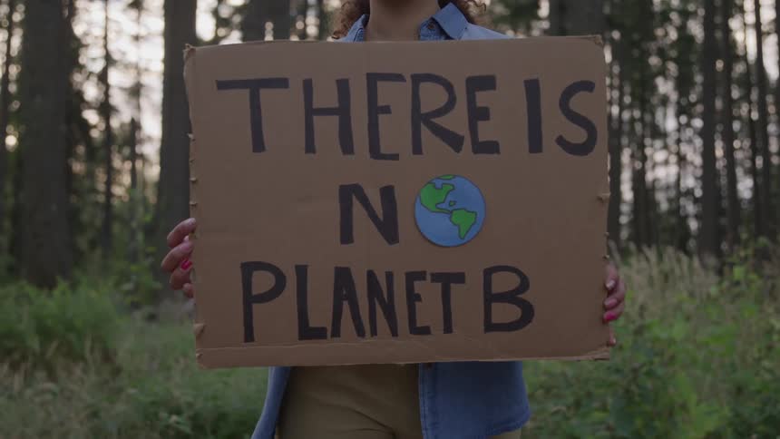 Person holds a sign with the phrase there is no planet b and a drawing of planet earth in the middle