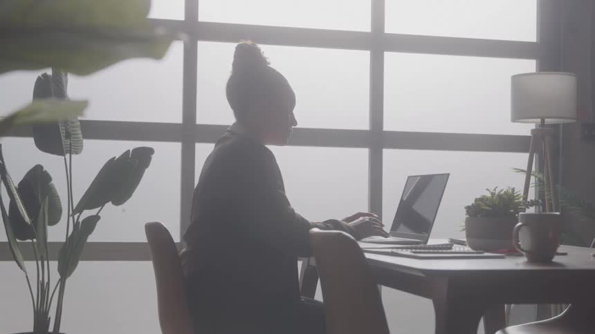 A woman types on a laptop