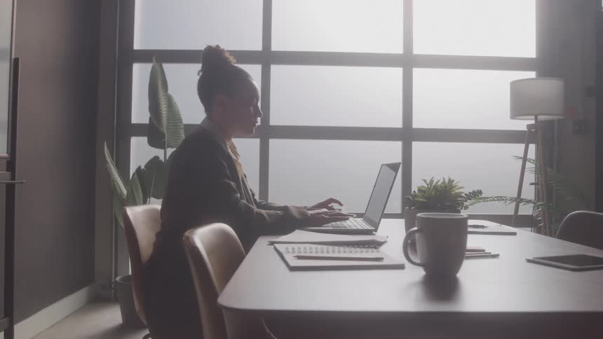 A woman types on a laptop