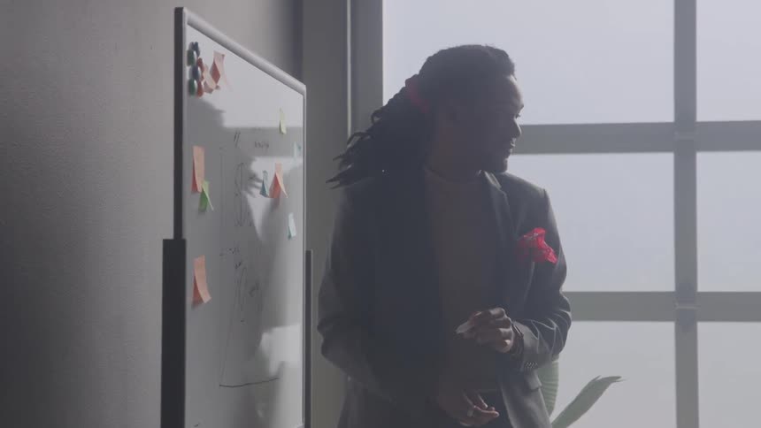 Man talking and writing on a whiteboard in an office room