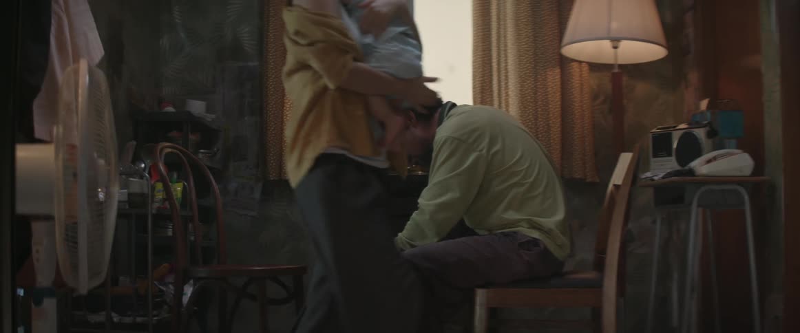 A man leans forward as a woman gets up walking away with a baby
