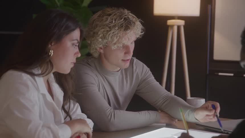 Three people collaborating in a meeting reviewing documents on the table