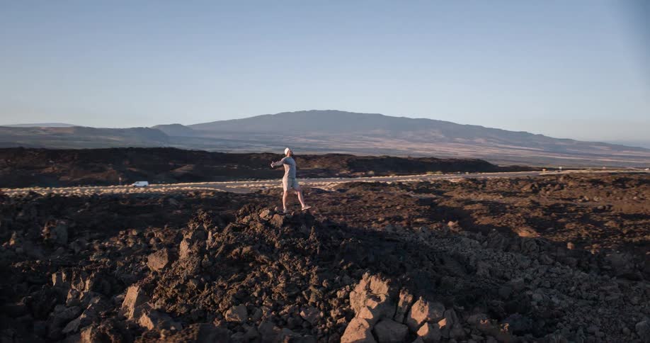 A man is standing on the rocks with his arms raised