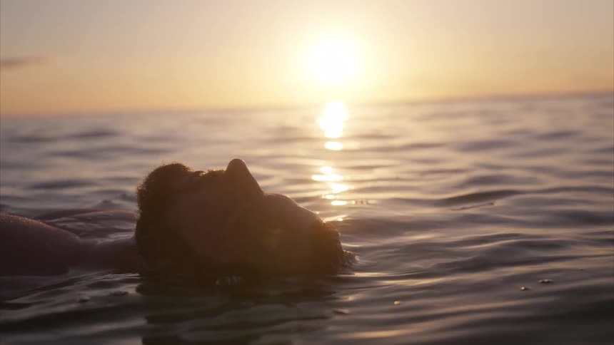 Person swimming in the sea during sunset