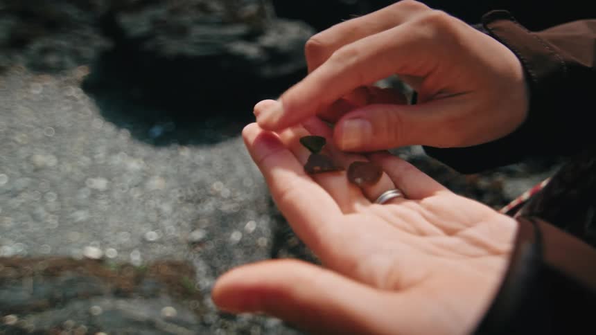 A person holding three triangular pebbles on one hand and touching them with the opposing index finger