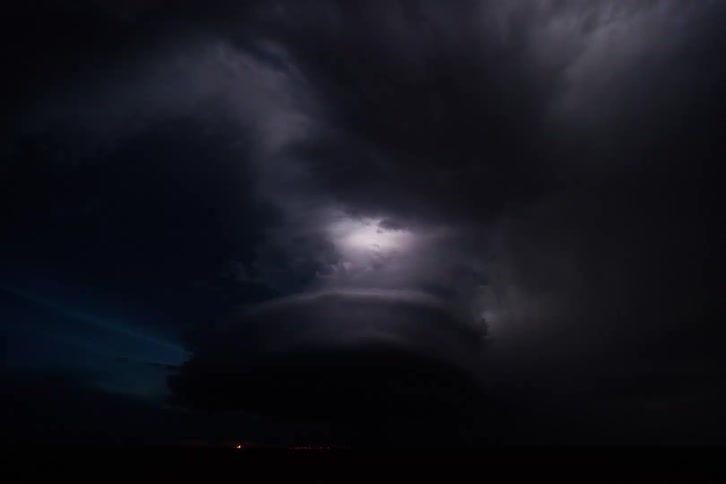 Lightning strikes through dark storm clouds over open land