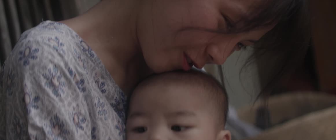 A woman smiles and kisses the top of a boys head