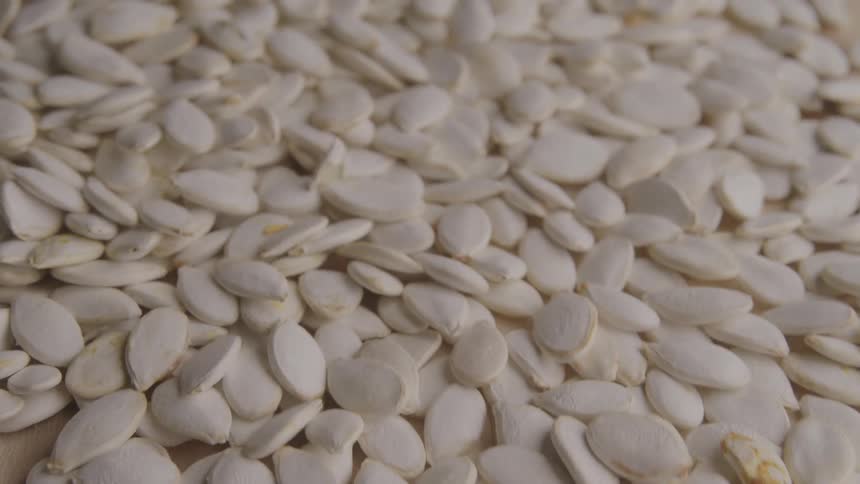A large pile of pumpkin seeds are sliding forward