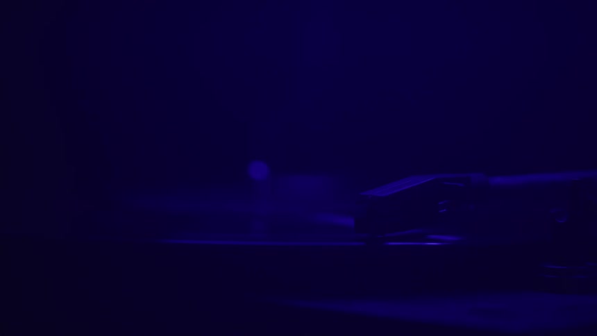 The video shows a dark shadowy scene with a small blue light coming from the right side of the screen the light source which is blurry and out of focus creates an eerie and suspenseful atmosphere