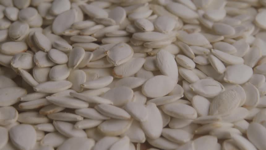 A close view of a pile of white pumpkin seeds sliding down
