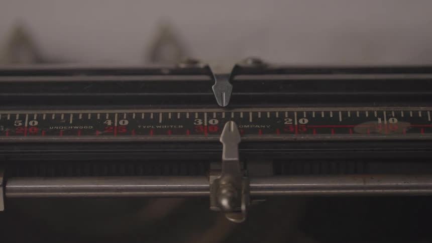 Closeup of a typewriter carriage with metal guides positioned over the measurement scale