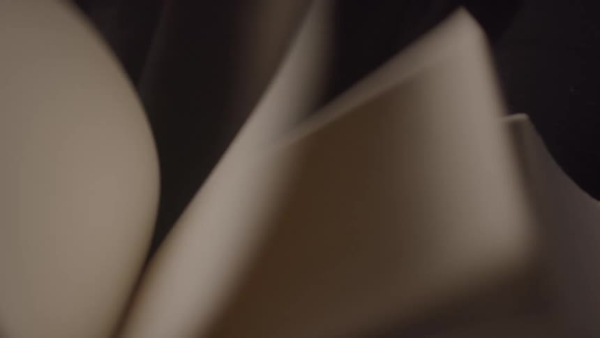 The video shows a book with pages turning quickly the pages have an orange tint to them and the book is opened in the middle