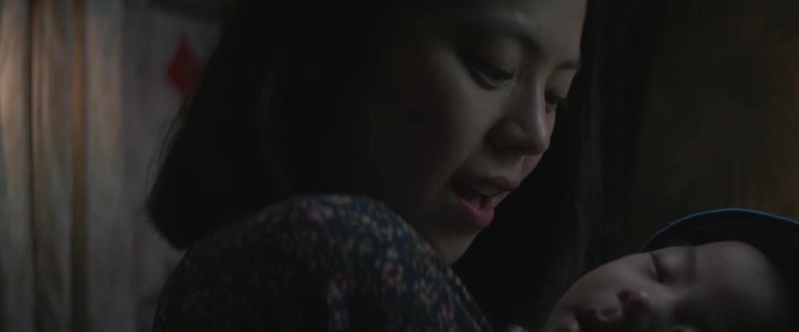 A close up view of a woman's shoulder as she holds a baby in her arms