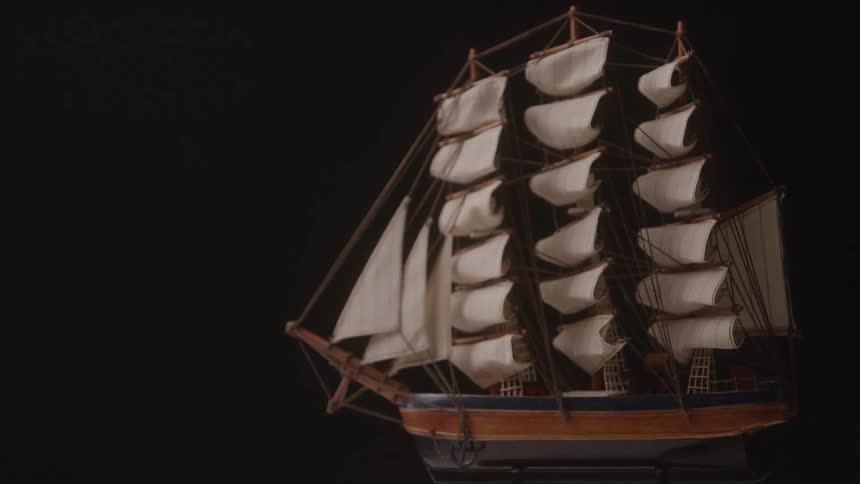 A highly detailed model of a sailing ship with multiple white sails is showcased against a plain black background